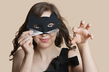 一名年轻女子戴着眼罩在彩色背景上模仿猫咪的肖像