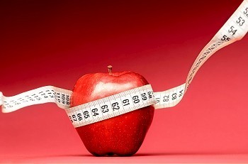 苹果摄影照片_健康食品。红底带卷尺的美味苹果