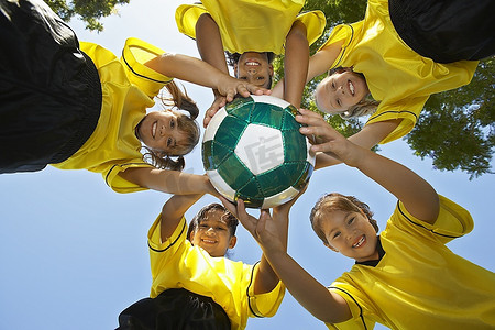 5名儿童(7-9岁)手持足球，从下往下看，肖像
