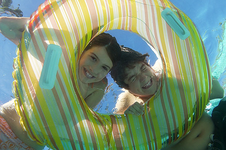 男孩和女孩在游泳池里透过充气筏看水下景色