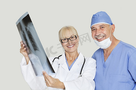 快乐的医疗同事的肖像，在灰色背景上有X光片