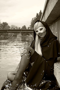 旧时尚B&W拍摄的性感金发女郎附近的河与狂欢节面具和丝袜