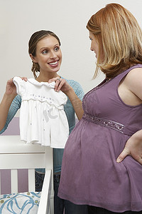 两个女人看着摇篮里的婴儿衣服