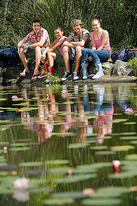 小溪边摄影照片_年轻的朋友们坐在小溪边