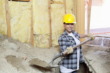快乐的女承建商在工地挖沙的肖像