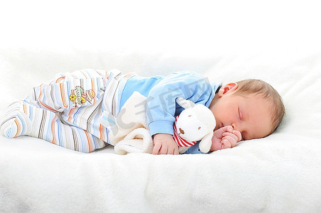 白色床摄影照片_睡在白色毯子上的玩具宝宝