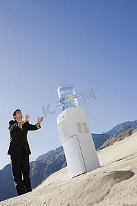 沙漠中站在饮水机旁的商人