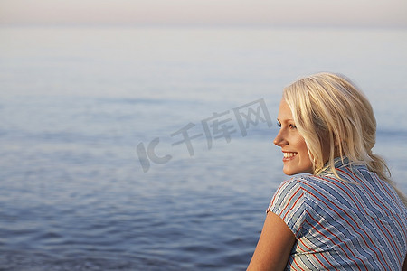 年轻女子坐在海滩，侧视图