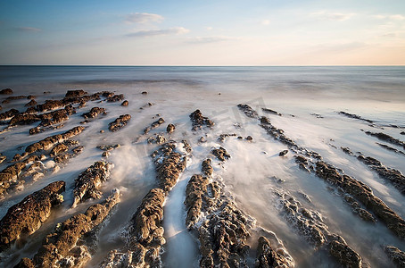长时间曝光运动模糊海洋的悬索网岩质海滩景观图像