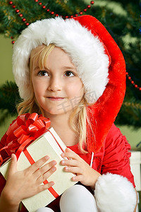 圣诞树附近戴着圣诞帽的漂亮小女孩