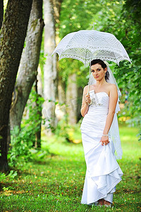 美丽的新娘撑着伞走在公园里