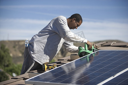 屋顶上的一名男子正在修理太阳能板