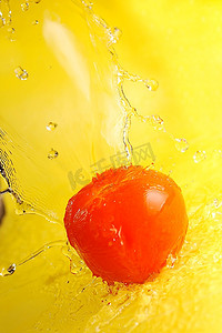 番茄和水飞溅在黄色近摄