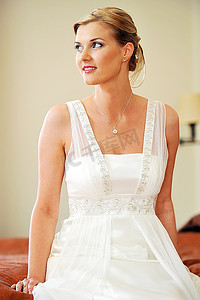 白色连衣裙摄影照片_漂亮时髦的新娘在房间里穿着白色连衣裙
