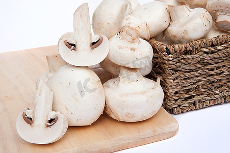 新鲜的香菇蘑菇，装在白色背景下孤立的乡村编织篮子里