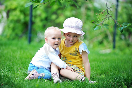 42195摄影照片_女孩和她的弟弟坐在草地上