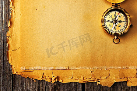 航海复古背景摄影照片_旧纸背景上的古董黄铜指南针