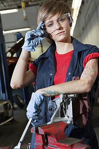 防护汽车摄影照片_车库里戴着防护眼镜的年轻女机械师的肖像