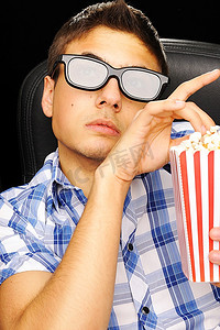 一名戴着3D眼镜的年轻人在电影院看电影
