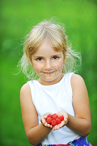 开心的微笑着的小女孩拿着树莓