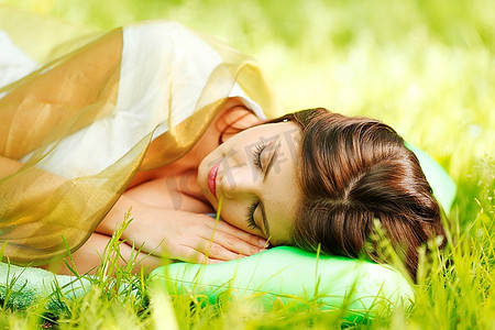 睡在柔软的枕头上的年轻女子，睡在新鲜的春草中