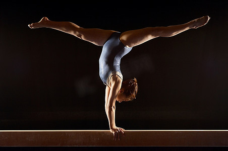 平衡木摄影照片_体操运动员在平衡木上做分体倒立