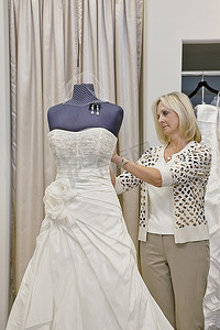 资深女店主在婚纱店调整模特的婚纱