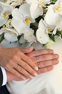 手戴结婚戒指和白色兰花花束