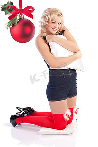 丝袜背景摄影照片_非常迷人性感的年轻金发女子，穿着短工装裤和红色丝袜，摆姿势摆姿势，带着枕头