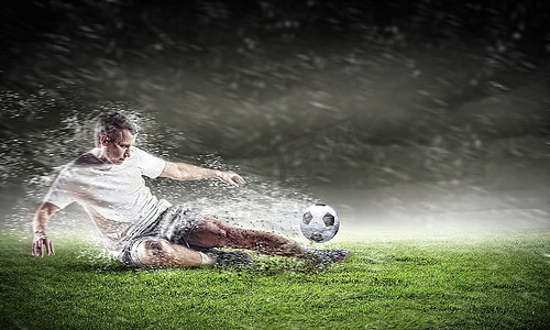 在雨中在体育场击球的白色衬衫的足球运动员