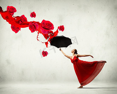 芭蕾舞演员在飞行缎礼服与伞和花
