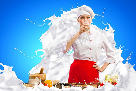 亚洲女厨师在喝牛奶的颜色背景下穿着红色围裙防止牛奶飞溅
