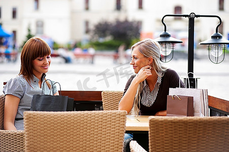 两个美丽而老练的年轻女性朋友坐在户外的咖啡馆里