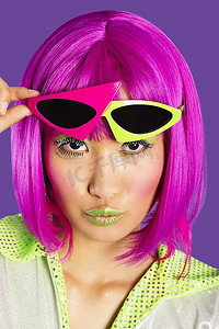 戴着粉色假发的年轻时髦女子的肖像，紫色背景上皱起嘴唇