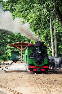 绿色的小老式蒸汽机车在轨道上行驶