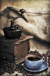 老式手工咖啡研磨机与咖啡豆和杯子
