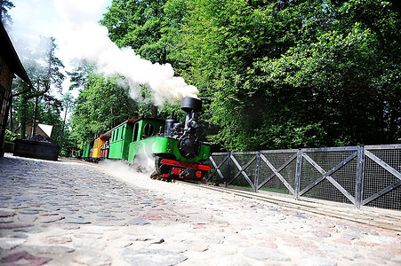 小绿色旧蒸汽机车骑在铁轨上