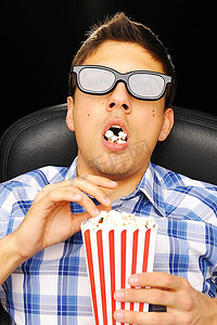 看电影摄影照片_一名戴着3D眼镜的年轻人在电影院看电影