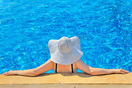 黑边摄影照片_戴着白帽子的女子在泳池边放松