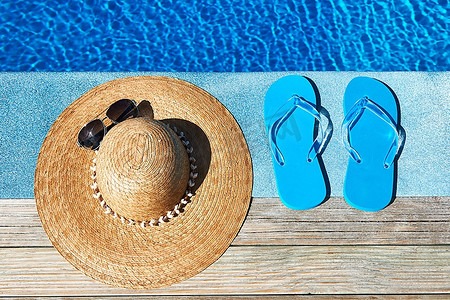 游泳池边的蓝色拖鞋和帽子