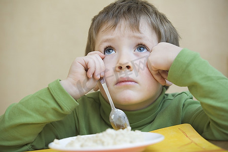 小男孩摄影照片_小男孩吃饭时抬头凝视的肖像