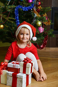漂亮的小女孩在圣诞树附近的圣诞帽