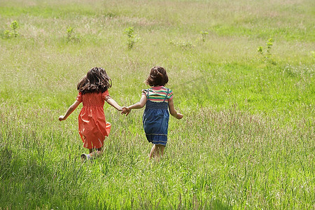 放肆奔跑放肆生長摄影照片_两个女孩在草地上奔跑