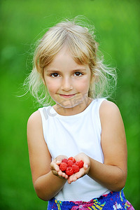 开心的微笑着的小女孩拿着树莓