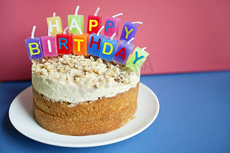 英语活动背景摄影照片_彩色背景上蛋糕上生日蜡烛的特写