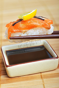蘸酱摄影照片_筷子间的寿司准备蘸酱汁