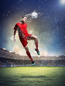 在红色衬衫的足球运动员在雨中在体育场击球
