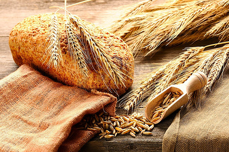 木质背景上的黑麦小穗和面包
