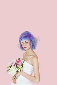 在粉色背景下，穿着婚纱，染着头发的美丽年轻女子的肖像