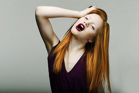 震惊。神经质的不快乐的红发女人沮丧地扯着头发。尖叫